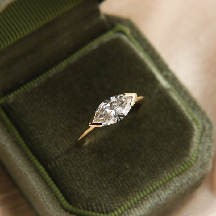 East west marquise moissanite angular bezel engagement ring on a fine yellow gold band