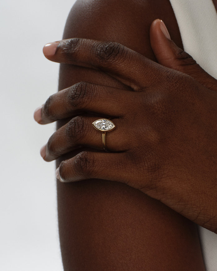 Marquise lab grown diamond bezel ring in yellow gold worn on a hand resting on the shoulder