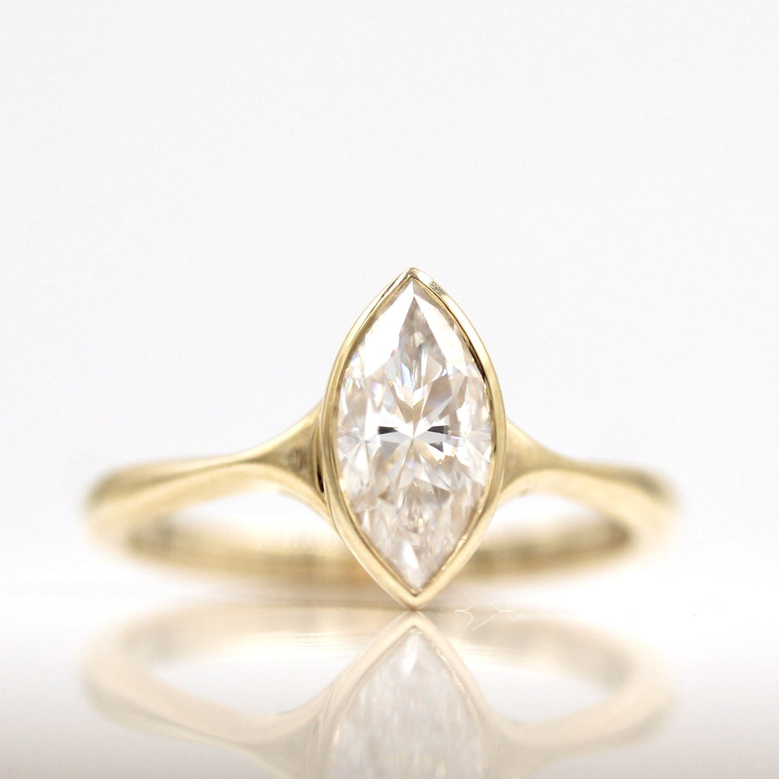 Marquise cut moissanite bezel engagement ring on a split tapering yellow gold shank