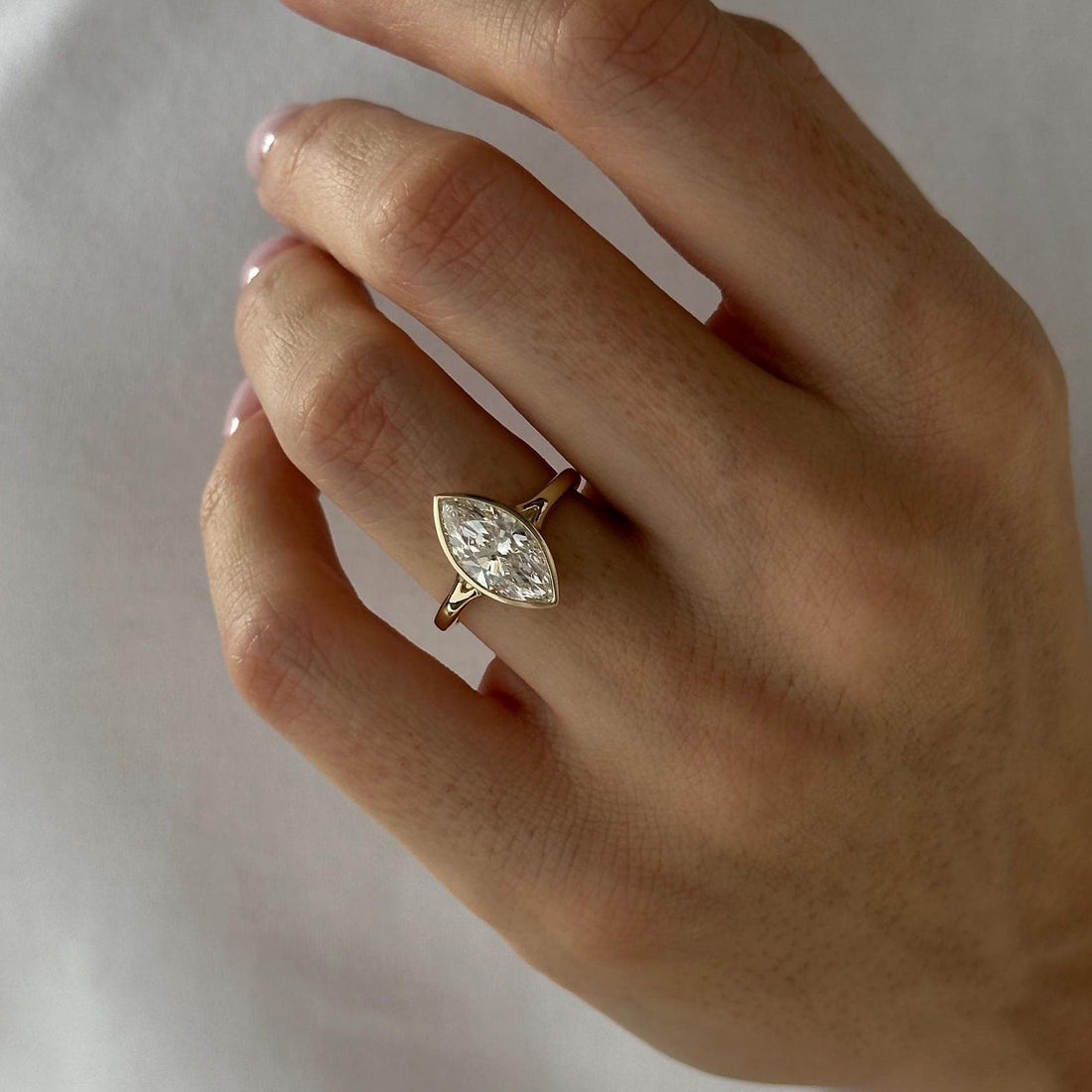 Marquise cut moissanite bezel set solitaire engagement ring in yellow gold