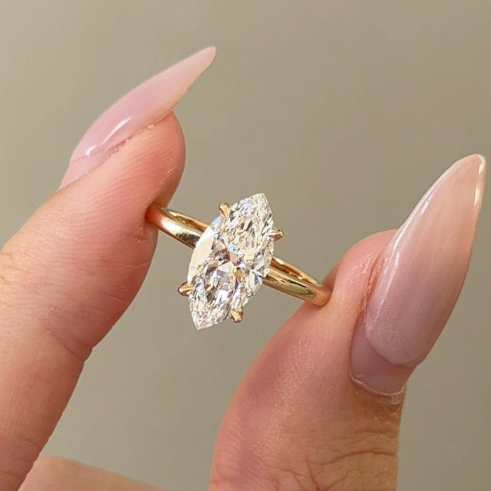 Marquise cut moissanite hidden halo engagement ring on a plain yellow gold band