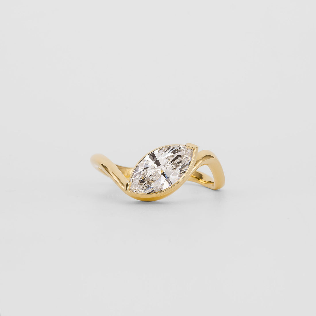 East west marquise moissanite half bezel engagement ring on a wave band in yellow gold