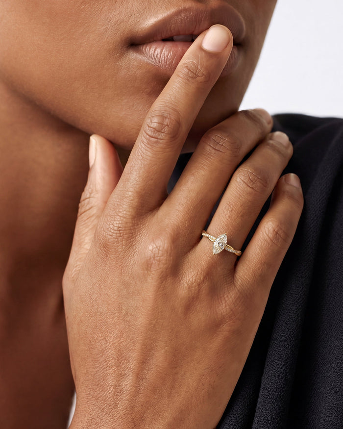Marquise lab grown diamond infinity twist ring on a hand held to the lips