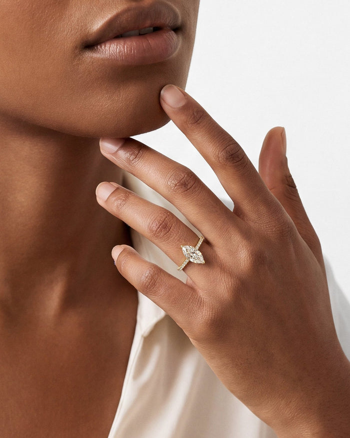 Marquise lab grown diamond pave band ring in yellow gold worn on the hand at the chin