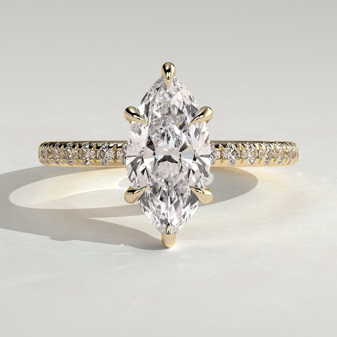 Marquise cut moissanite six claw engagement ring on a pave yellow gold band