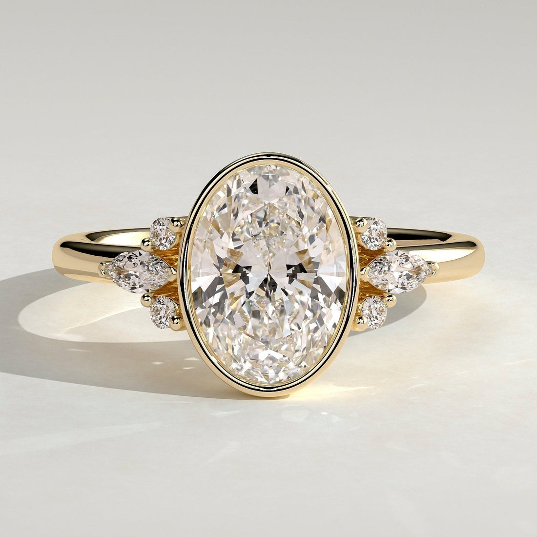 Oval cut moissanite bezel engagement ring with marquise cluster shoulders in yellow gold