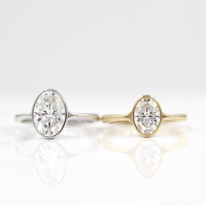 Oval cut moissanite bezel engagement ring on a pinched tapered yellow gold band, view 2