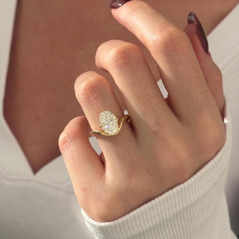 Oval cut moissanite curved bypass solitaire engagement ring in yellow gold