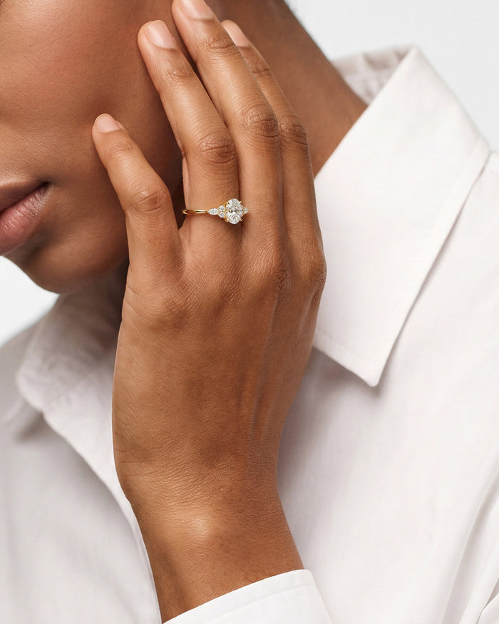 Oval moissanite vintage style ring with marquise accents in yellow gold worn on the hand at the face