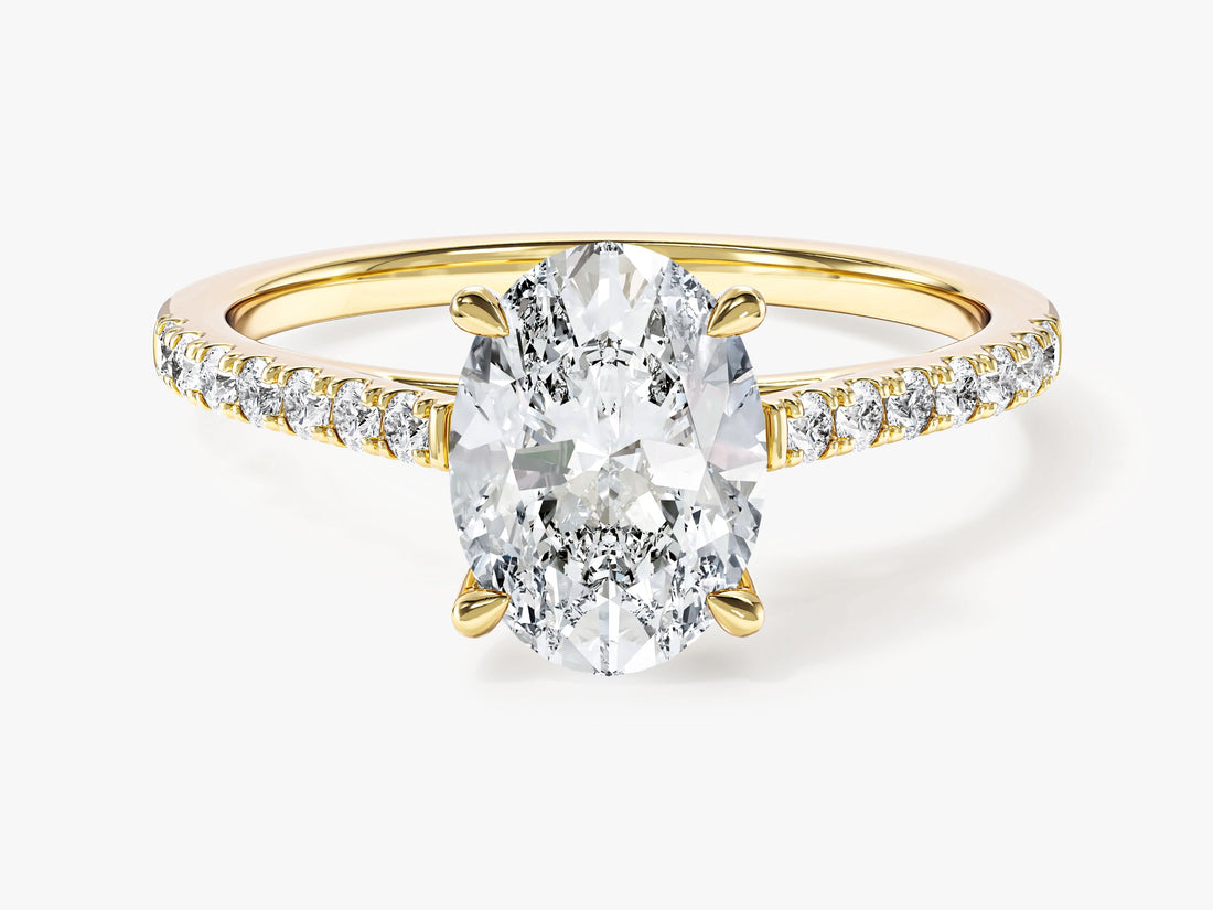 Oval moissanite four claw solitaire engagement ring with micro pave shoulders in yellow gold, front view