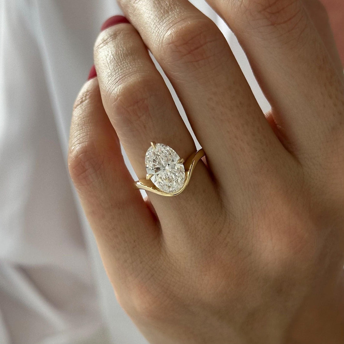Oval cut moissanite curved wave solitaire engagement ring in yellow gold