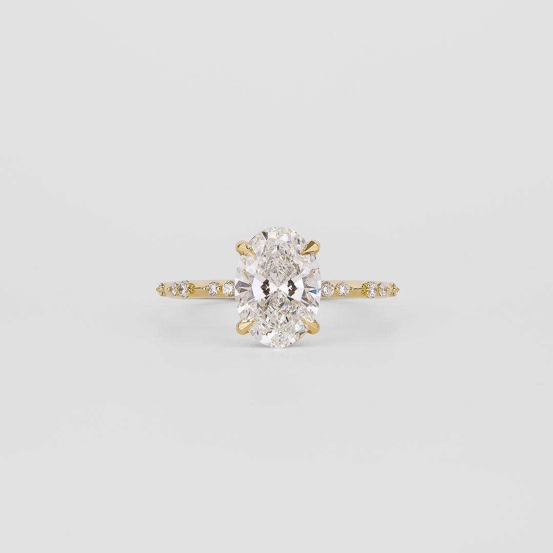 Oval cut moissanite engagement ring on a dainty spaced accent yellow gold band