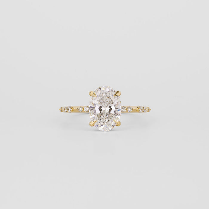 Oval cut moissanite engagement ring on a dainty spaced accent yellow gold band