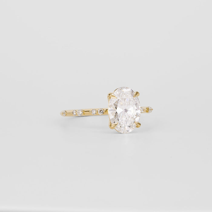 Oval cut moissanite engagement ring on a dainty spaced accent yellow gold band, view 2