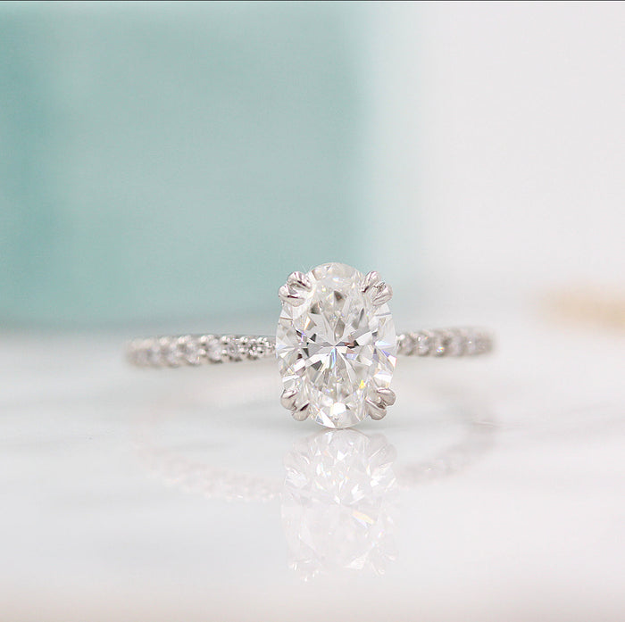 Oval cut moissanite double claw engagement ring on a French pave band in white gold