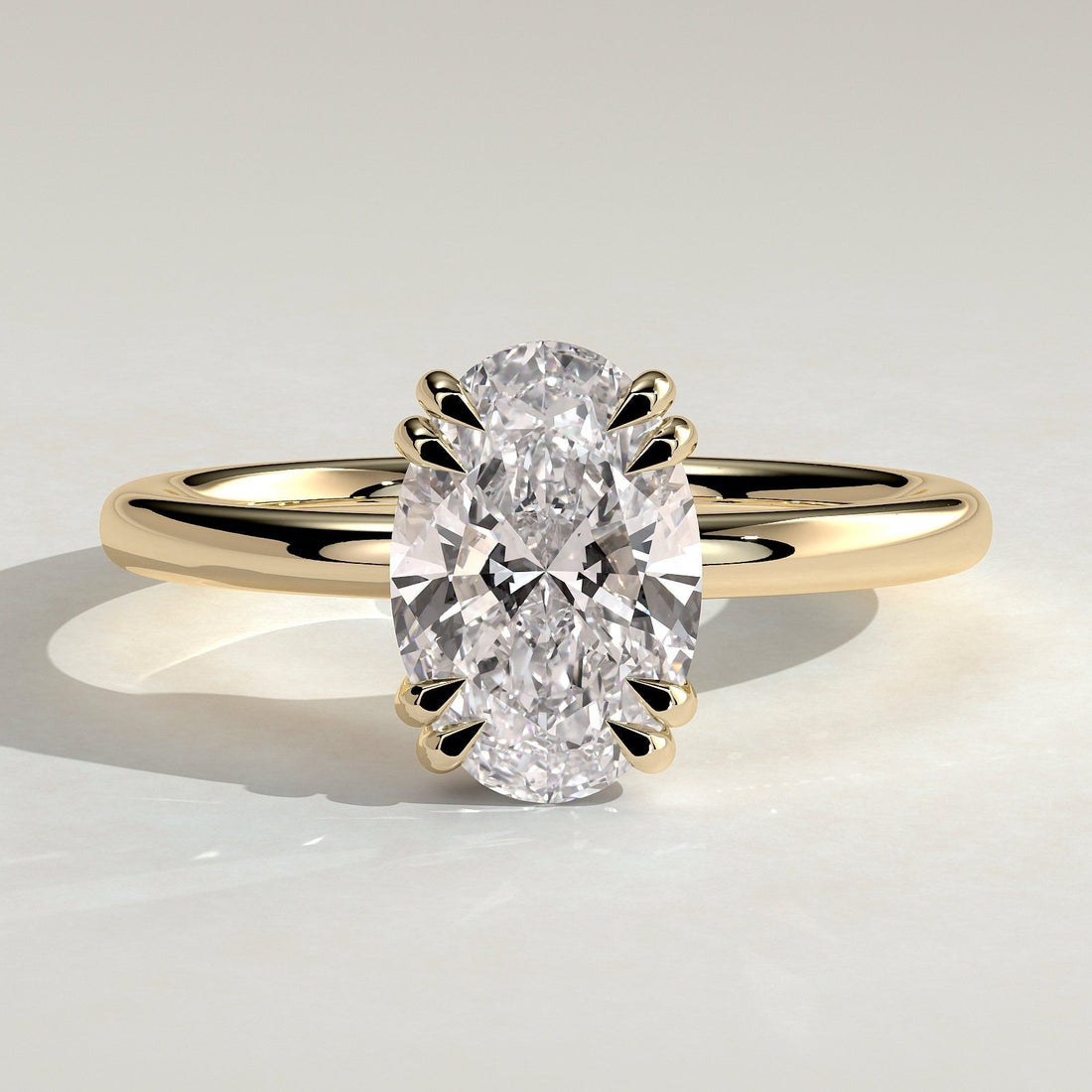 Oval cut moissanite double claw solitaire engagement ring on a knife edge yellow gold band