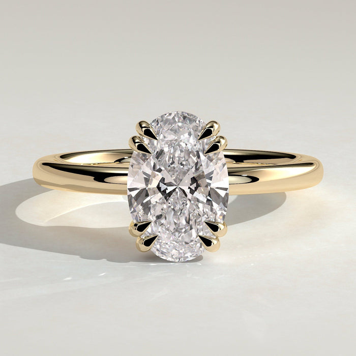 Oval cut moissanite double claw solitaire engagement ring on a knife edge yellow gold band