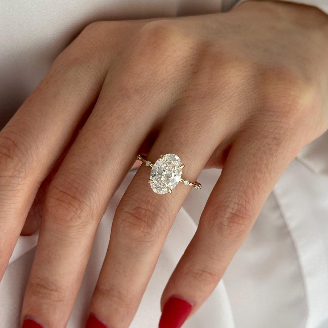 Dainty oval cut moissanite engagement ring on a thin pave band in yellow gold