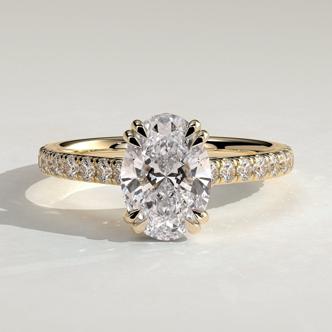 Oval cut moissanite double claw engagement ring on a pave yellow gold band