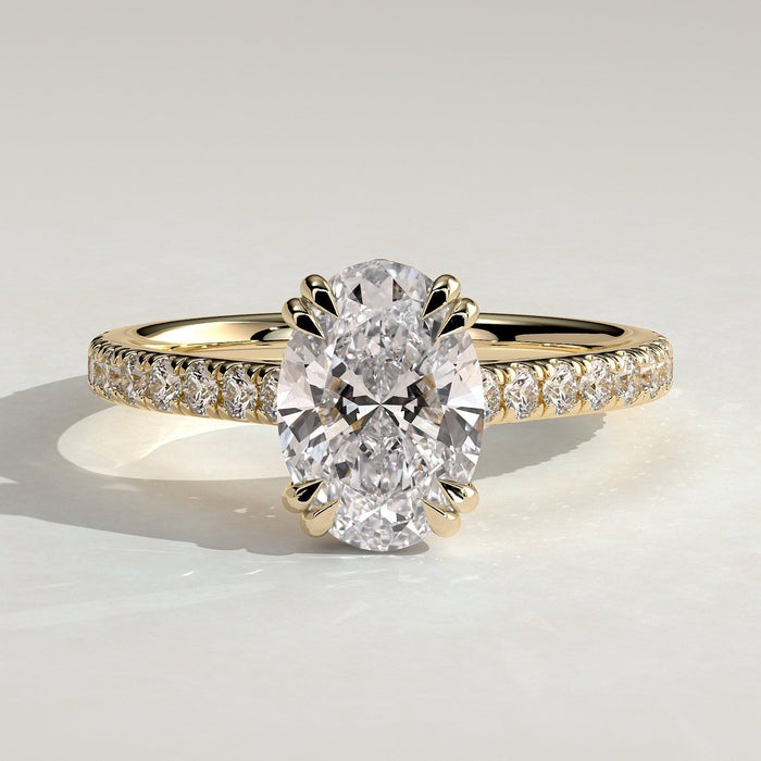 Oval cut moissanite double claw engagement ring on a pave yellow gold band