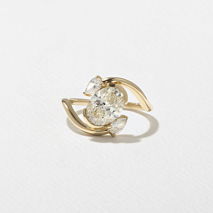 Oval cut moissanite diagonal swirl three stone engagement ring with pear accents in yellow gold