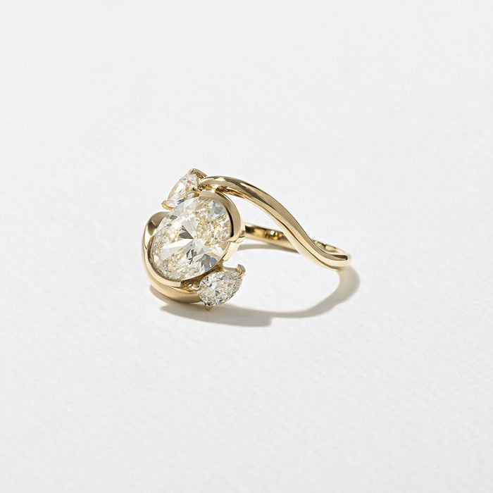 Oval cut moissanite diagonal swirl three stone engagement ring with pear accents in yellow gold, view 2