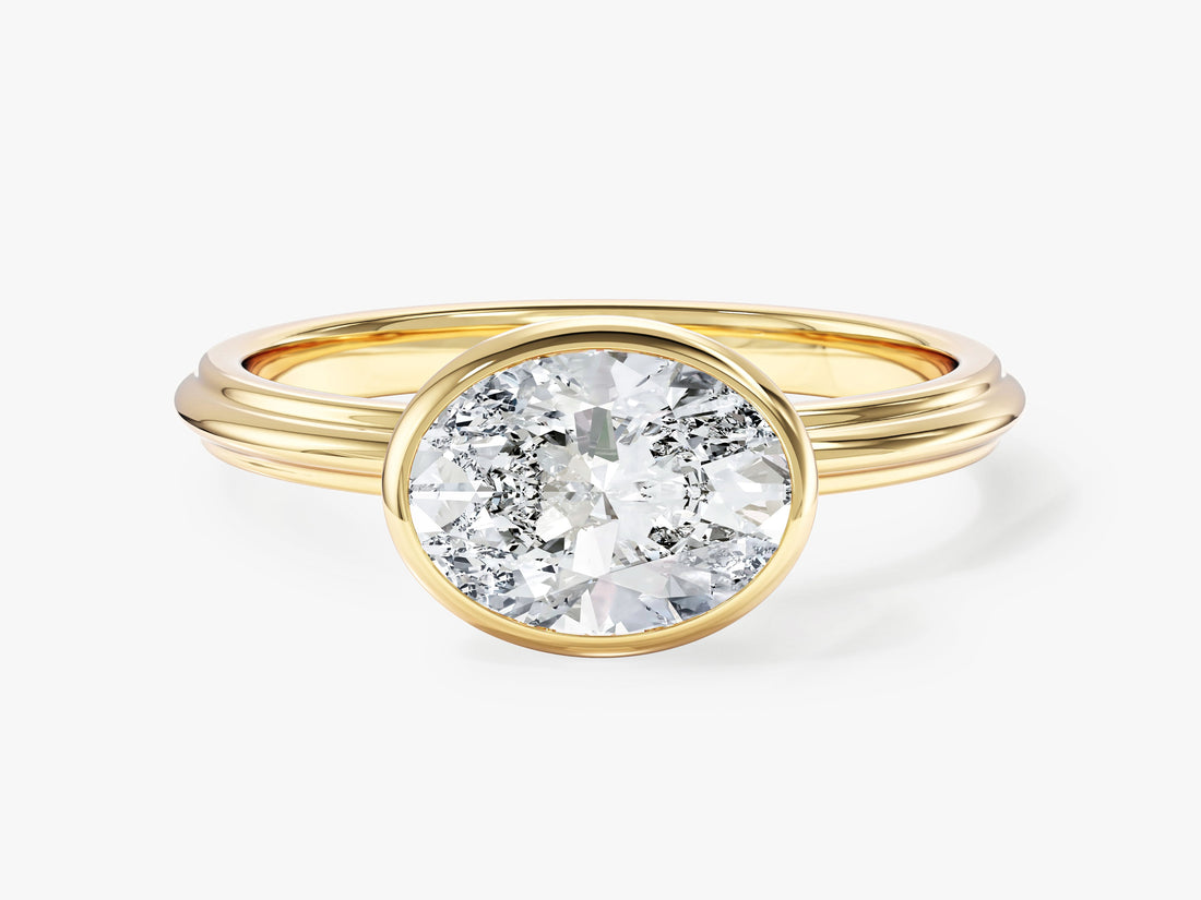East west oval lab grown diamond bezel solitaire ring with stepped band in yellow gold, front view
