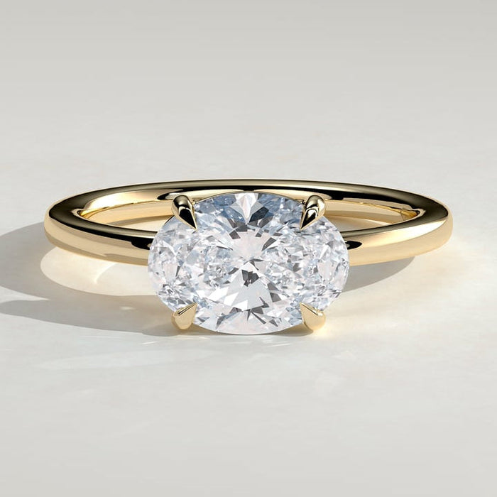 East west oval moissanite four claw solitaire engagement ring on a plain yellow gold band