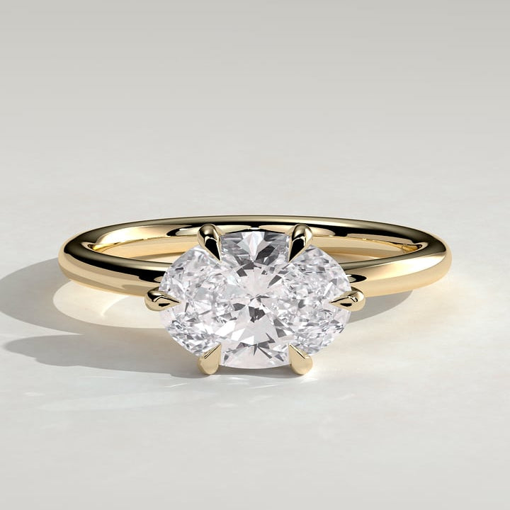 East west oval moissanite six claw solitaire engagement ring on a plain yellow gold band