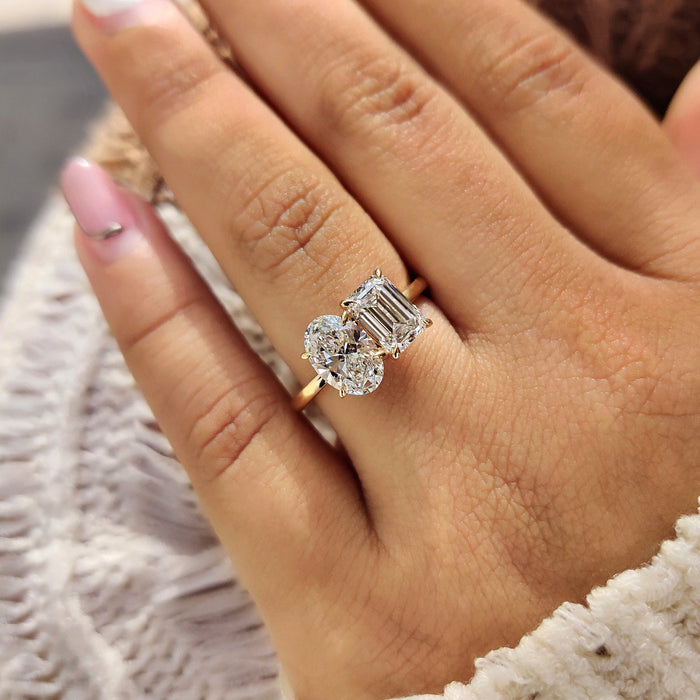 Oval and emerald cut moissanite toi et moi engagement ring on a plain yellow gold band, view 2