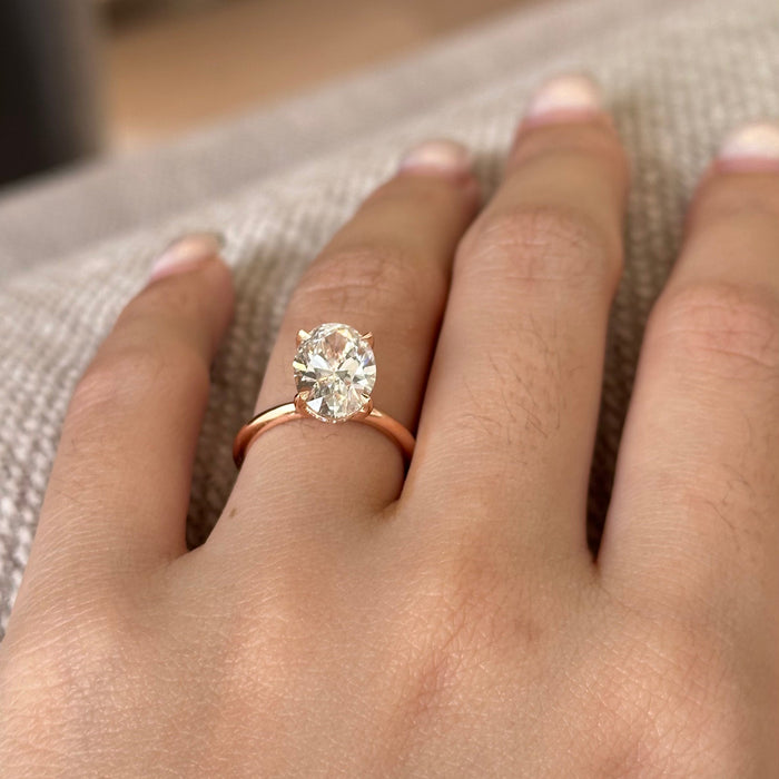 Oval cut moissanite four claw solitaire engagement ring on a fine rose gold band, view 2