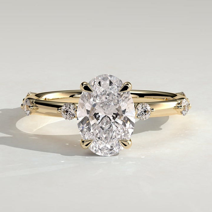 Oval cut moissanite engagement ring with graduated spaced accents in yellow gold