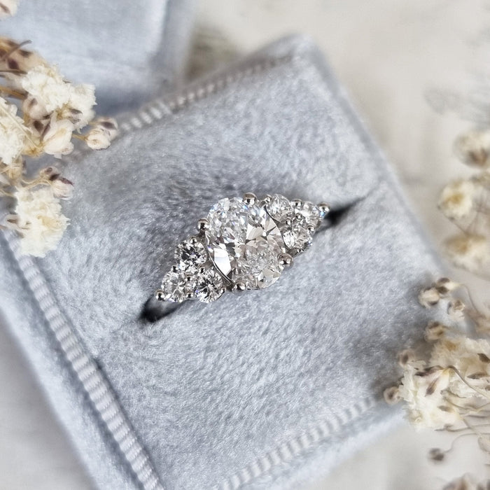Oval cut moissanite graduated round cluster shoulder engagement ring in white gold