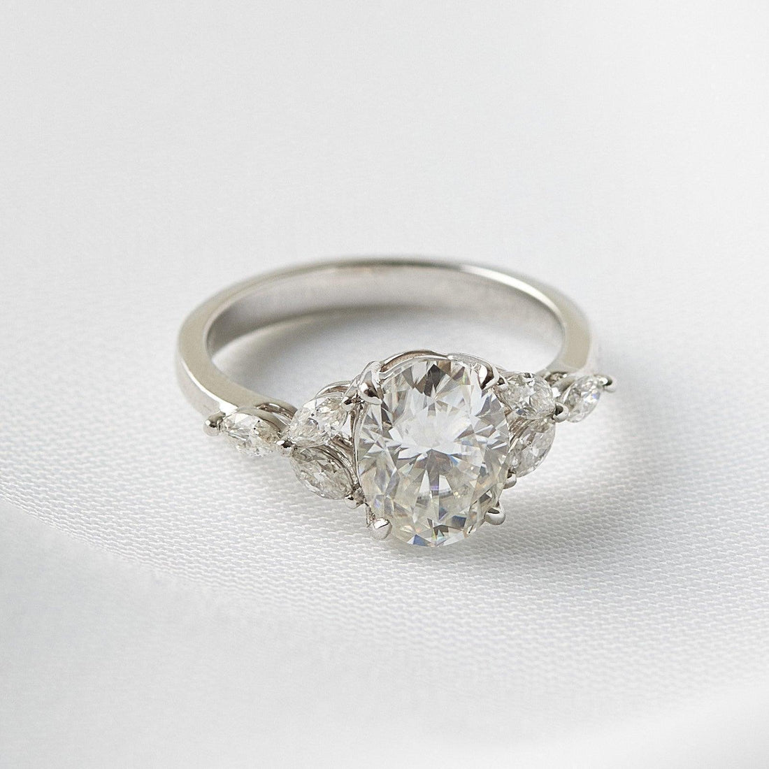 Oval cut moissanite engagement ring with graduated marquise shoulders on a flat white gold band