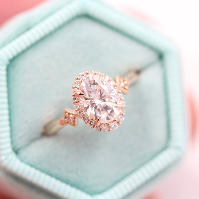 Oval cut moissanite graduated halo engagement ring with star panels at the shoulders in rose gold