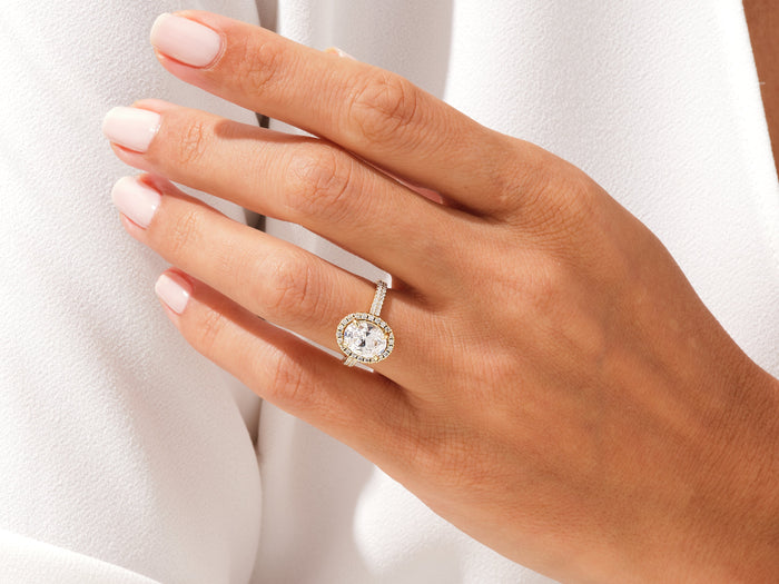 Oval moissanite halo ring with two row pave band worn on the ring finger
