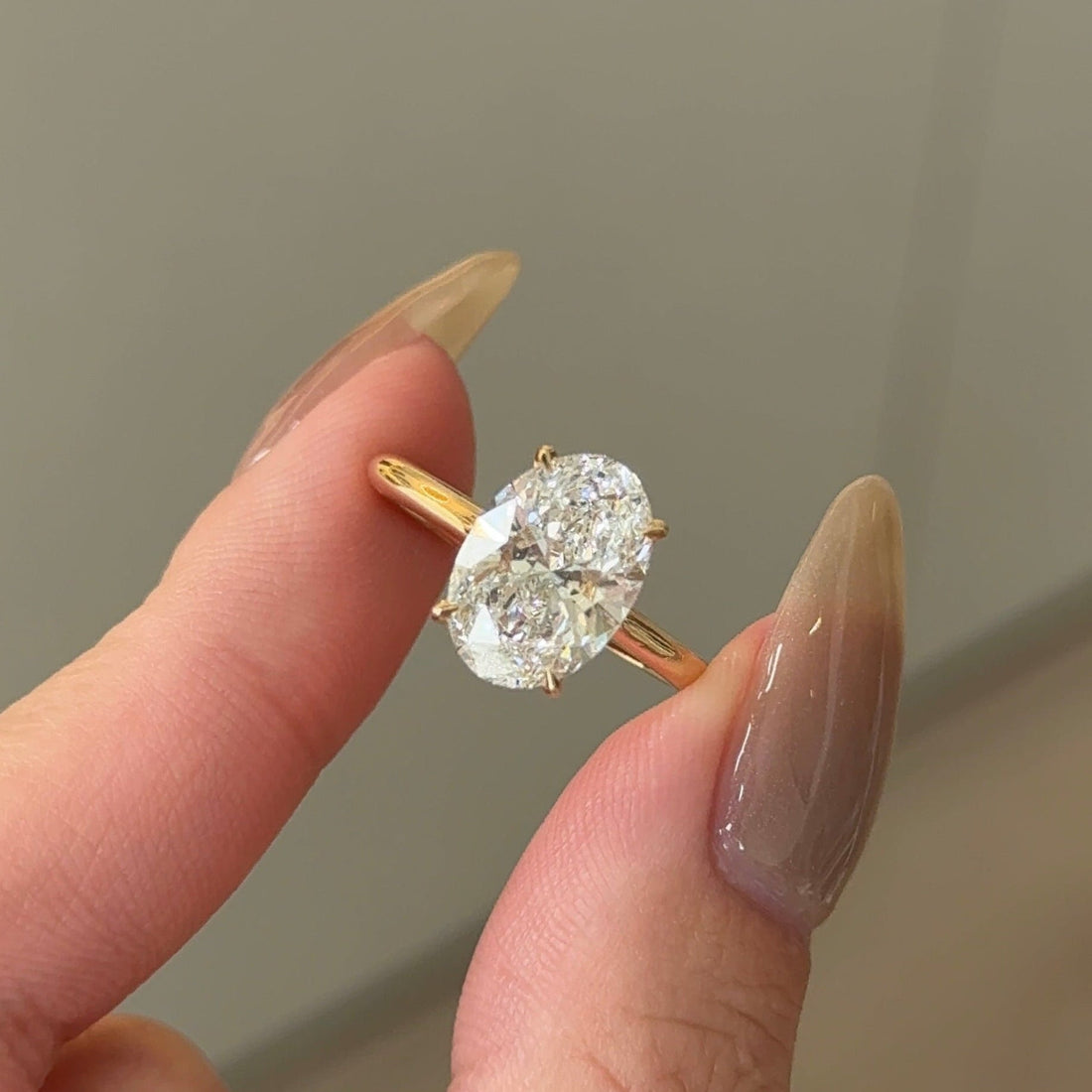 Oval cut moissanite hidden halo engagement ring on a knife edge yellow gold band