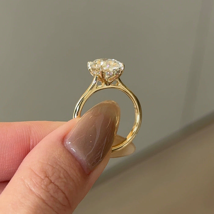 Oval cut moissanite hidden halo engagement ring on a knife edge yellow gold band, view 2