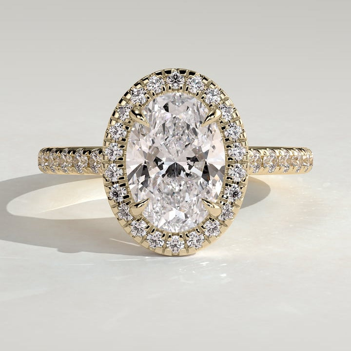 Oval cut moissanite halo engagement ring on a pave yellow gold band