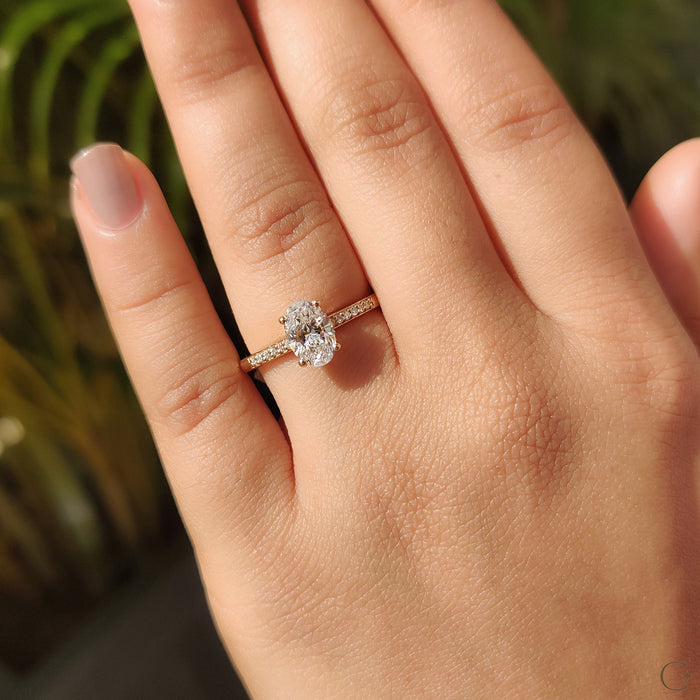 Oval cut moissanite four claw engagement ring on a half pave yellow gold band, view 2