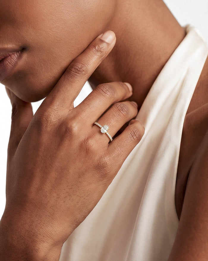 Oval moissanite pave band ring with hidden halo in yellow gold worn on the hand at the chin