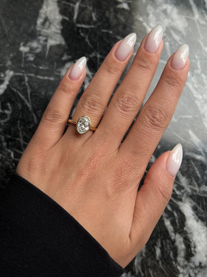 Oval cut moissanite heavy rim bezel solitaire engagement ring on a fine yellow gold band, view 2