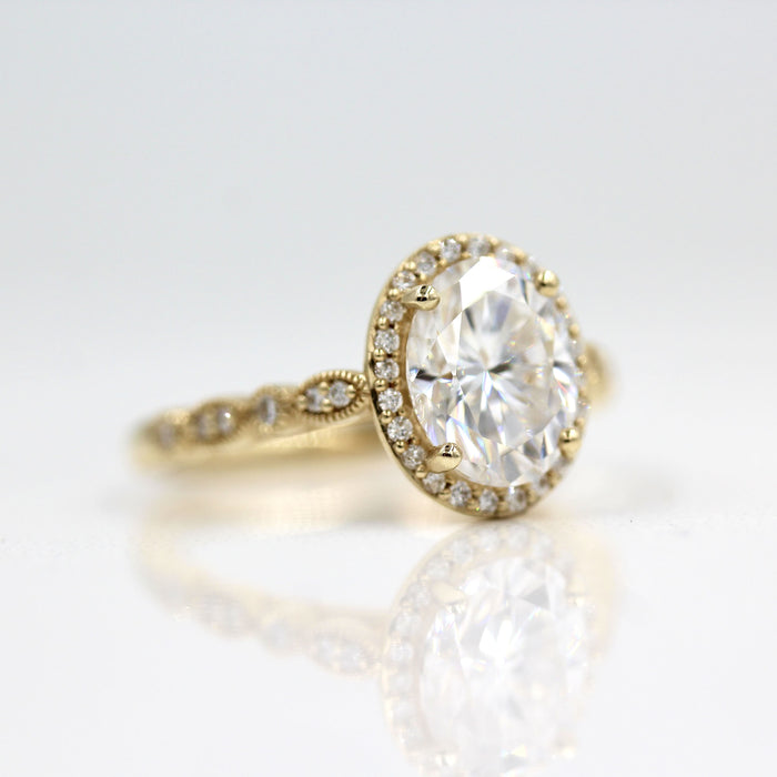 Oval cut moissanite halo engagement ring on a scalloped milgrain band in yellow gold, view 2