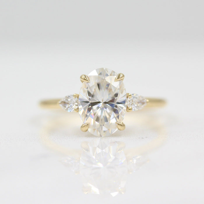 Large oval cut moissanite three stone engagement ring with pear sides on a fine yellow gold band