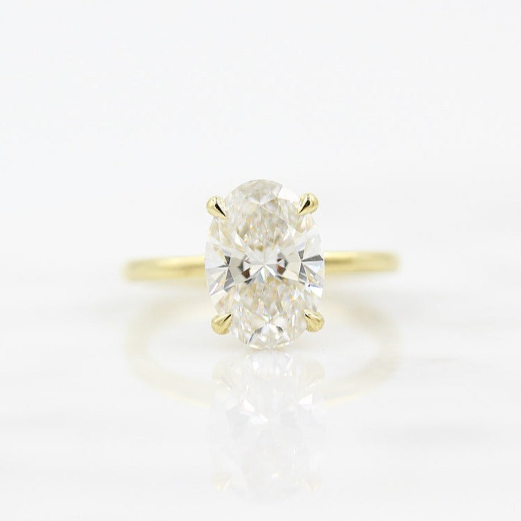 Large oval cut moissanite solitaire engagement ring on a hairline wire yellow gold band