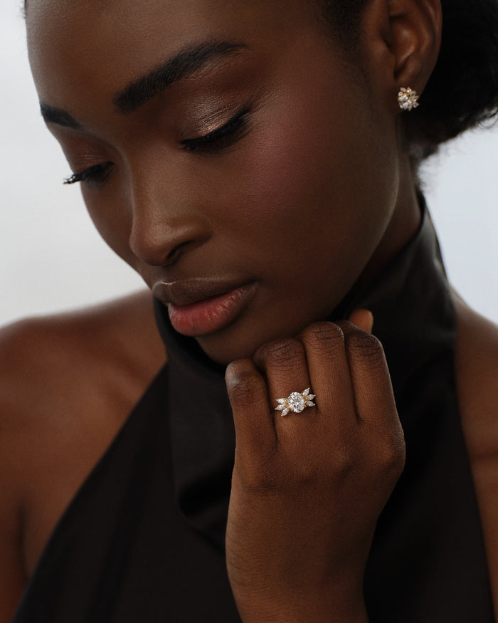 Oval moissanite marquise cluster ring in rose gold worn on the hand held under the chin