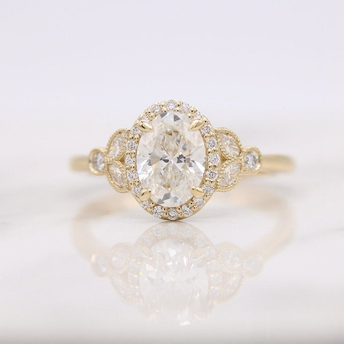 Oval cut moissanite milgrain halo engagement ring with marquise panels at the shoulders