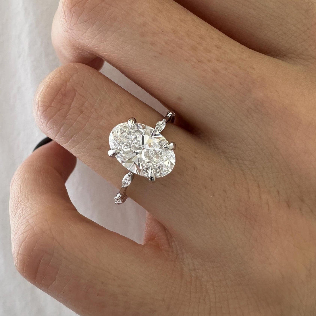 Oval cut moissanite engagement ring with marquise station band in white gold