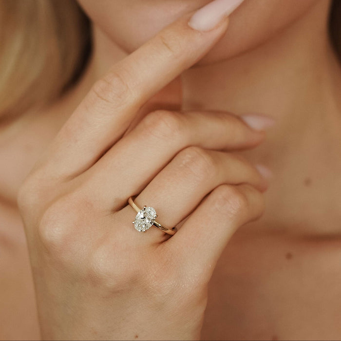 Oval cut moissanite pointed claw solitaire engagement ring on a rounded yellow gold band, view 2