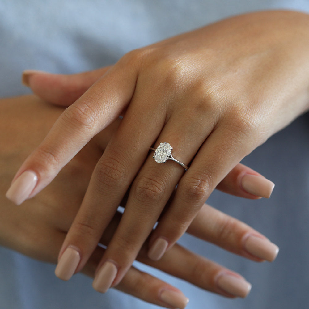 Oval cut moissanite solitaire engagement ring on a pinched tapered hairline band in white gold